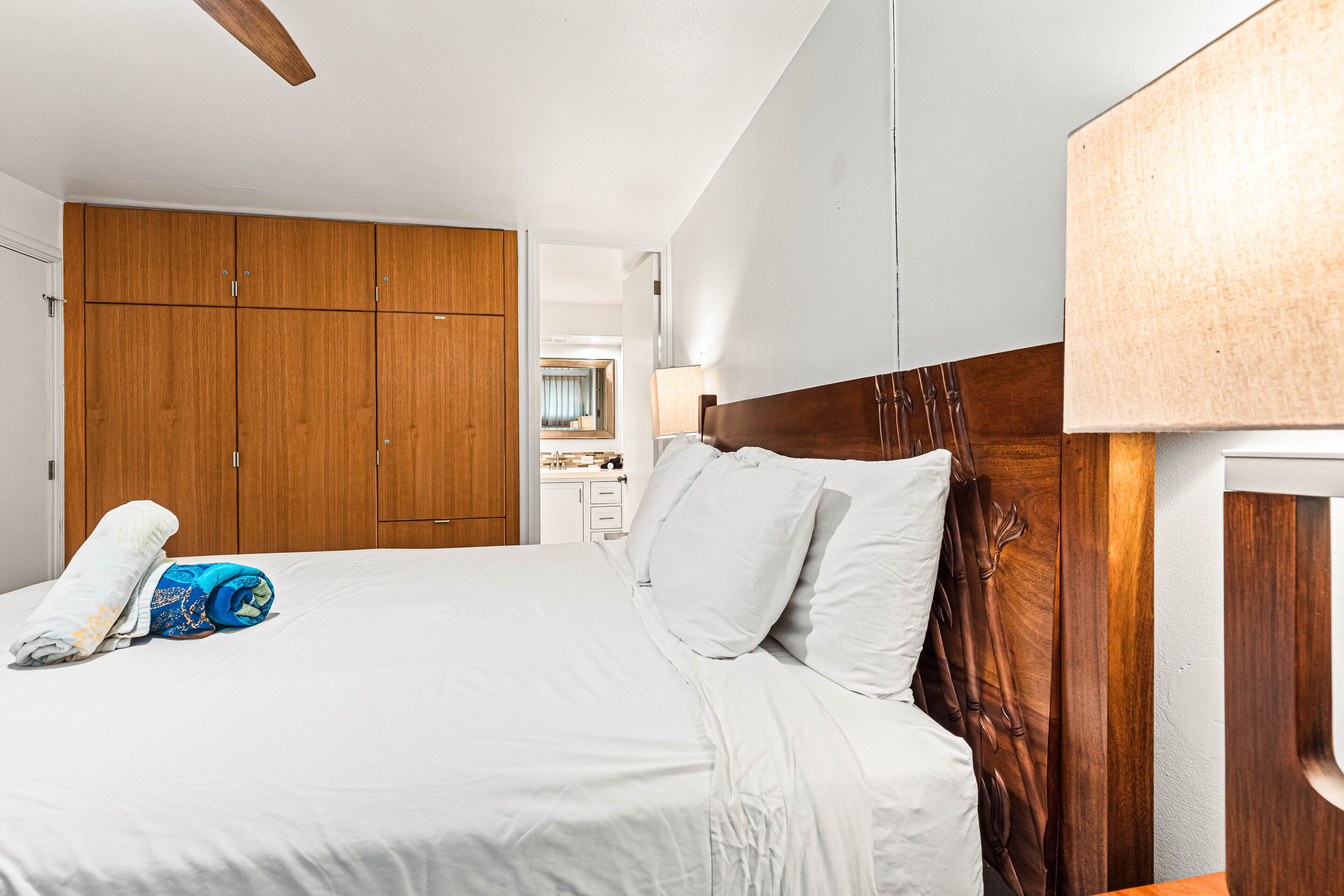 Habitación de hotel con una cama grande, un armario de madera y un baño a la vista.