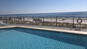 Una piscina con acqua cristallina e trasparente, circondata da una spiaggia sabbiosa e da una recinzione metallica.