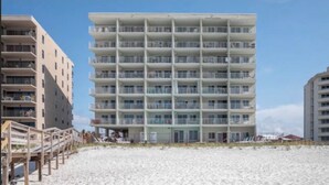 Un hotel a più piani con balconi, situato su una spiaggia sabbiosa.