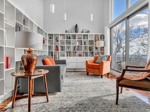 Un salon moderne avec une grande bibliothèque, un canapé, un fauteuil et une table.