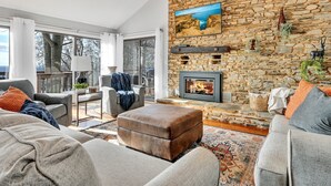 Een ruime woonkamer met een stenen muur, een open haard en een groot raam met uitzicht op een prachtig landschap.