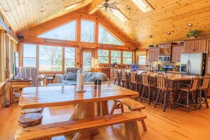 A spacious cabin with a large dining area, wooden furniture, and a kitchen with modern appliances. - Log Lover's Dream on Sand Point (Pigeon)