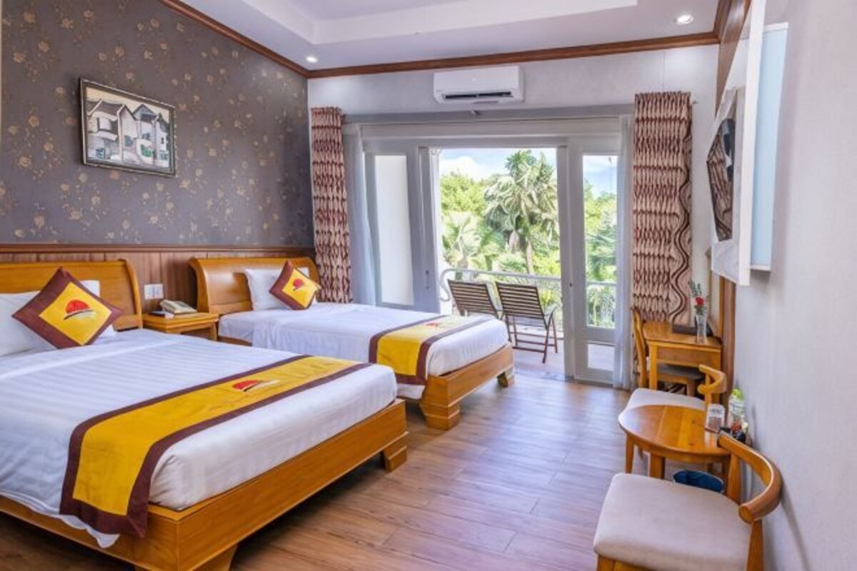 A hotel room with two beds, a balcony, a wooden chair, and a desk.