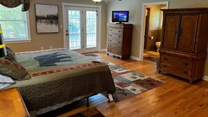 A bedroom with a bed, dresser, television, and a ceiling fan.