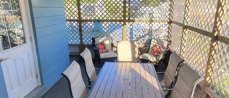 An outdoor patio with a table and chairs, a ceiling fan, and a lattice screen.