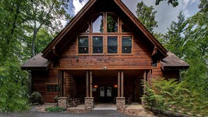 A log cabin with a prominent gable roof, large windows, and a stone foundation. - Arrowhead Lodge #568 (Gatlinburg)