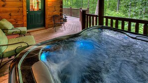 A hot tub on a wooden deck with a view of a forest. - Arrowhead Lodge #568 (Gatlinburg)