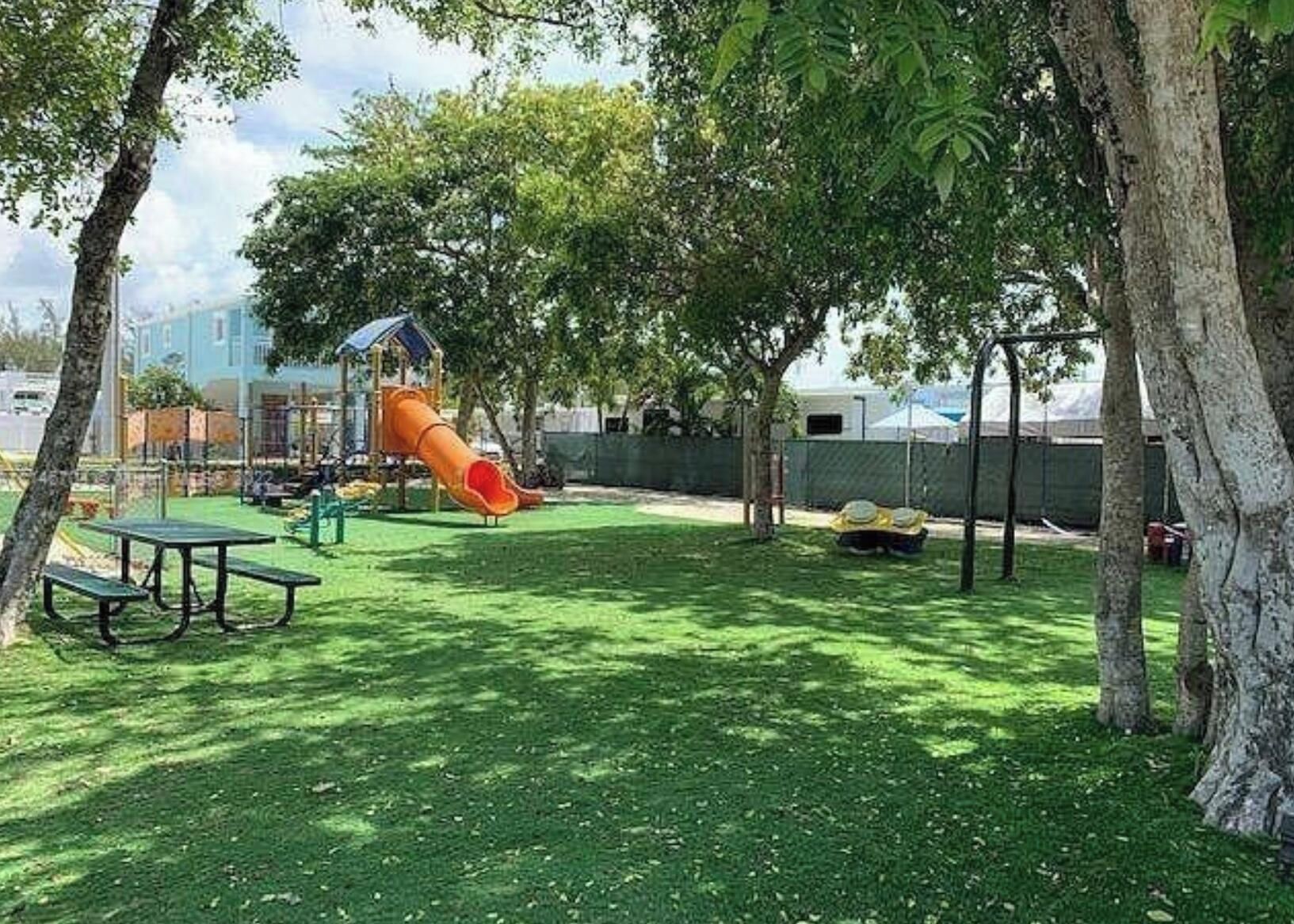 A playground with a slide and picnic tables in a grassy area.