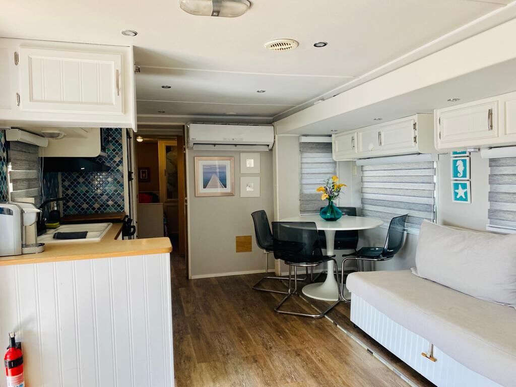 Interior compacto de una caravana con kitchenette, comedor y sofá.