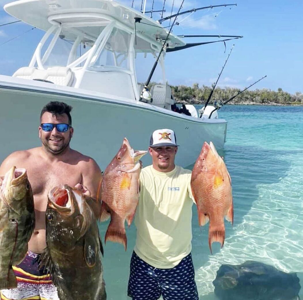 Un bateau avec deux personnes tenant des poissons, un ciel dégagé et une eau calme.