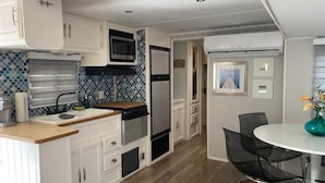 A compact kitchen with white cabinets, a microwave, a stove, and a sink. There is a dining area with a round table and chairs. - Perfect little paradise spot in key largo Florida.     (lot 15) (Key Largo)