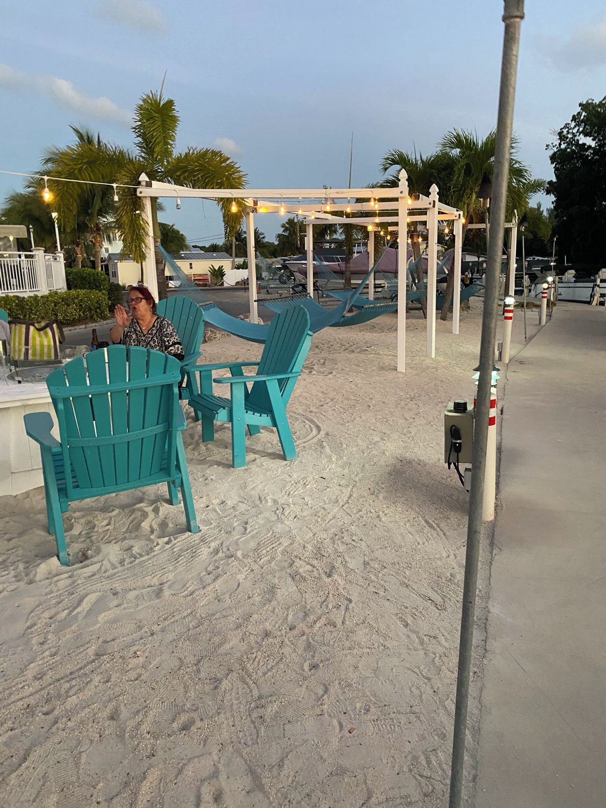 A beachside seating area with turquoise chairs and a wooden pergola.