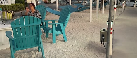 A beachside seating area with turquoise chairs and a wooden pergola.