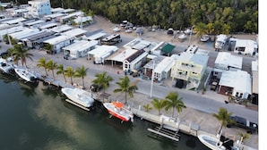 An aerial view of a marina with boats docked, a road lined with buildings, and palm trees. - Perfect little paradise spot in key largo Florida.     (lot 15) (Key Largo)