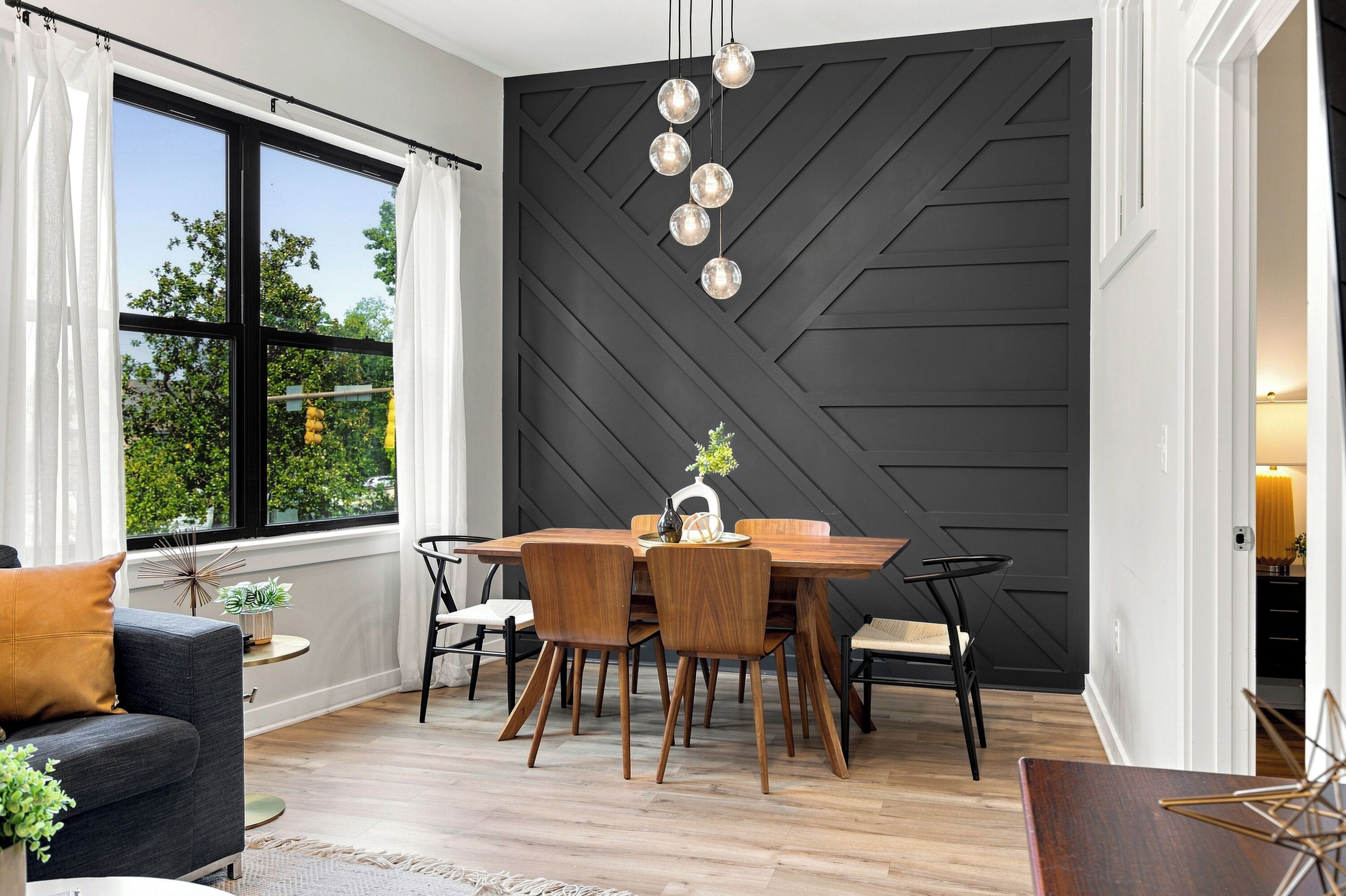 A modern dining area with a black geometric wall, wooden dining table, and chairs.