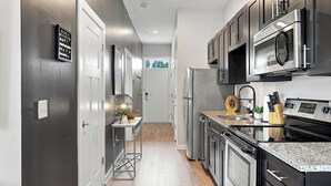 A modern kitchen with stainless steel appliances, a granite countertop, and a view to the outside.