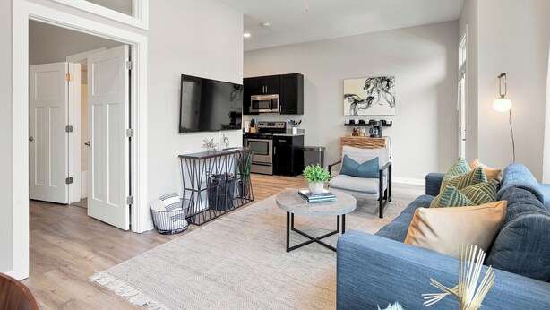 A modern living room with a sofa, coffee table, and a TV mounted on the wall.