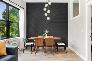 Un comedor moderno con una pared geométrica negra, una mesa de comedor de madera y sillas.