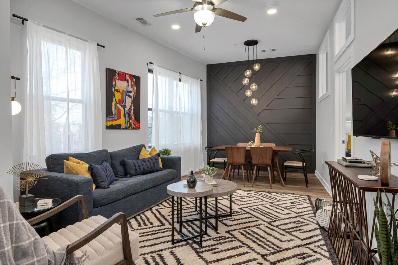 Una sala de estar moderna con un sofá gris, una mesa de centro redonda y un comedor con una mesa y sillas de madera.