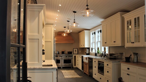 Una cocina moderna con armarios blancos, una isla central e iluminación colgante.