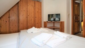 Una habitación de hotel con una cama, armario de madera y televisor.