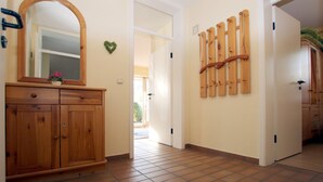 Een gang met een houten kast, een spiegel en een wandrek.