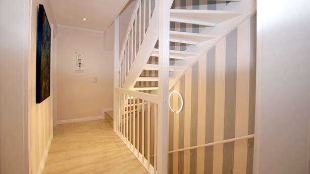 A staircase with white railings and a striped wall.