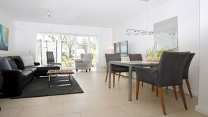 A modern living room with a sofa, coffee table, dining table with chairs, and a TV.