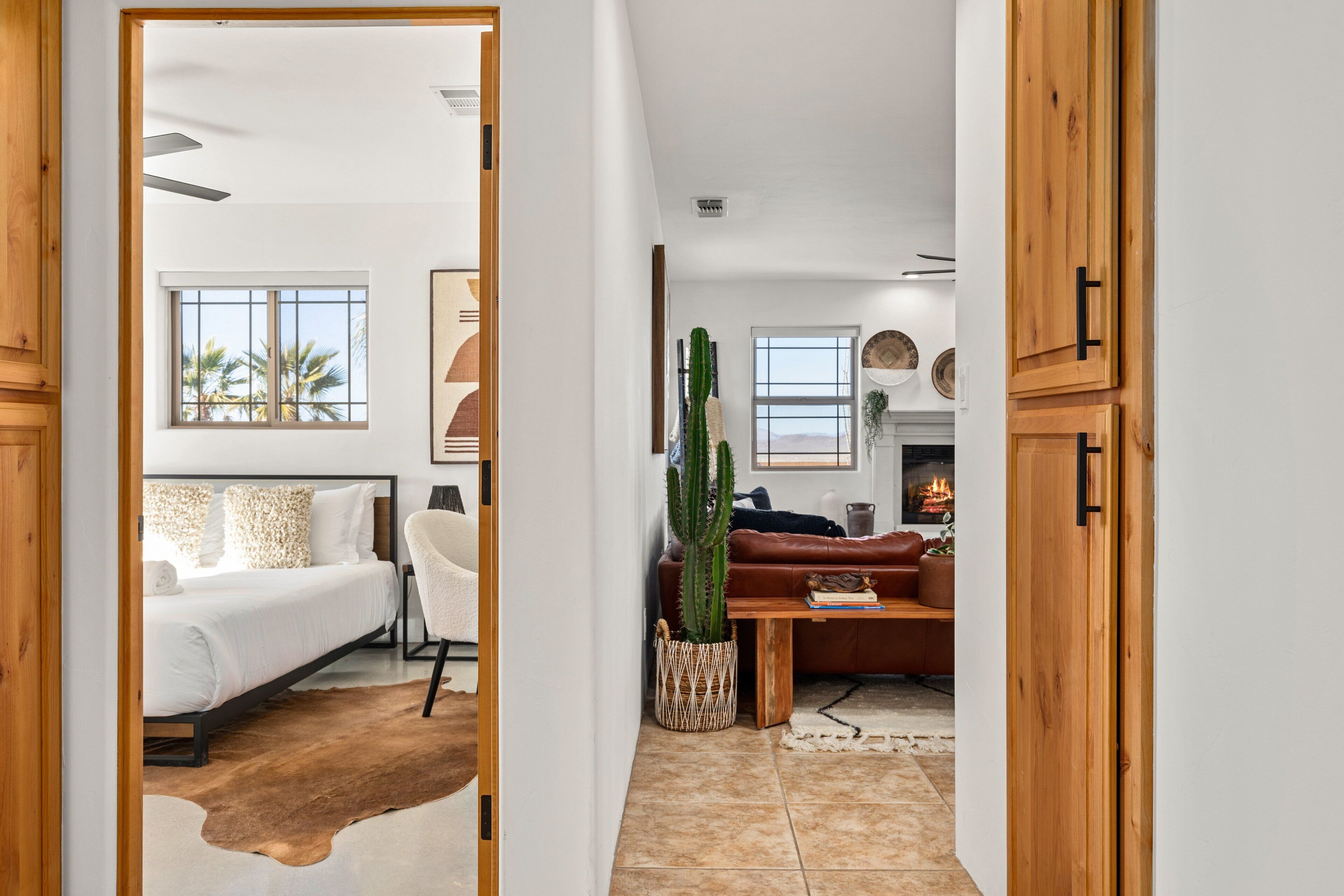 Un intérieur moderne avec un lit, une chaise blanche, une table en bois et un cactus.