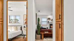 Un interior moderno con una cama, una silla blanca, una mesa de madera y una planta de cactus.