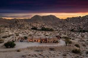 A desert landscape with a modern building featuring multiple rooms and a covered outdoor area.