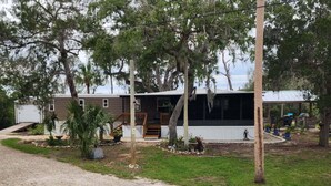 A single-story house with a front porch, a covered outdoor seating area, and a visible garage. - Waterfront Canal Cottage, Kayaks & Canoes, Minutes from Springs & Manatees! (Crystal River)