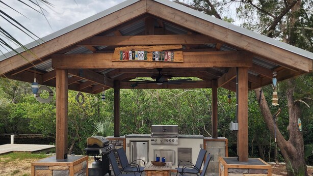 A covered outdoor barbecue area with a grill, seating, and a sign reading "RENTWOOD COTTAGE". - Waterfront Canal Cottage, Kayaks & Canoes, Minutes from Springs & Manatees! (Crystal River)