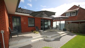 A patio with outdoor furniture, a brick wall, and a grassy lawn. - Schmalstieg 11 a, Wyker Perle - Holiday home with 3 rooms on approx. 81m² (Wyk auf Föhr)