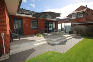 A patio with outdoor furniture, a brick wall, and a grassy lawn.