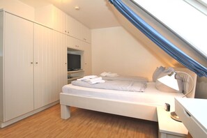 A bedroom with a bed, a TV, a desk, and a wardrobe.