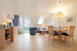 A cozy, well-lit room with a dining table, chairs, a sofa, and a lamp.