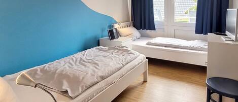 Ein Schlafzimmer mit zwei Betten, einem Schreibtisch und einem Stuhl.