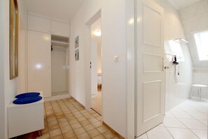 A modern bathroom with white tiles, a shower area, and a small stool.