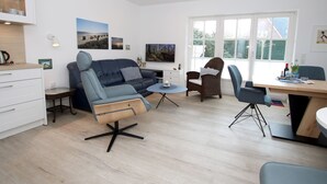 A modern living room with a sofa, chairs, a dining table, and artwork on the walls. - Olhörnstieg 6, Whg. 2 Inselliebe - Apartment with 3 rooms on approx. 53m² (Wyk auf Föhr)