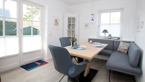 A modern dining area with a table, chairs, and a sofa. - Olhörnstieg 6, Whg. 2 Inselliebe - Apartment with 3 rooms on approx. 53m² (Wyk auf Föhr)
