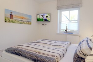 Un dormitorio con cama, ventana con vistas y dos cuadros en la pared.