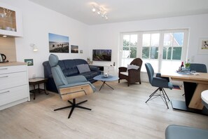 A modern living room with a sofa, chairs, a dining table, and artwork on the walls. - Olhörnstieg 6, Whg. 2 Inselliebe - Apartment with 3 rooms on approx. 53m² (Wyk auf Föhr)