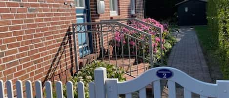 A brick house with a white picket fence, a pathway, and a sign indicating 'WORSTING 2'.