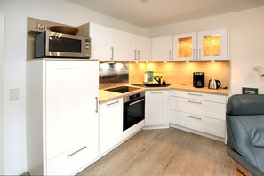 A compact kitchen with white cabinetry, a microwave, a coffee maker, and a sink. - Olhörnstieg 6, Whg. 2 Inselliebe - Apartment with 3 rooms on approx. 53m² (Wyk auf Föhr)