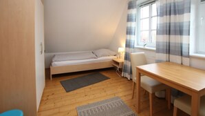 Une petite pièce agréable, dotée d’un lit simple, d’une table et d’une chaise.