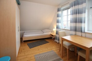 A small, cozy room with a single bed, a table, and a chair.