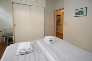 Un dormitorio con cama, una silla, un armario y un pasillo que lleva a un baño.
