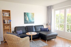 A living room with a sofa, a round coffee table, a bookshelf, and a painting. - Badestraße 18a, Whg. 1 - vacation apartment with 3 rooms, approx. 60m², in the center of Wyk, (Wyk auf Föhr)