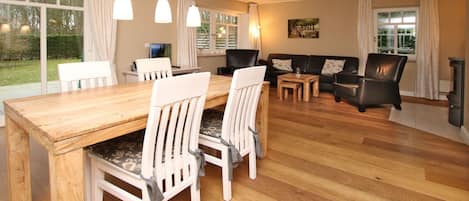 Een eethoek met een houten tafel en stoelen, een bank en een open haard.